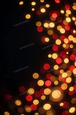 Defocused golden and red Christmas light bokeh orbs glowing on a deep black night background with wide empty copy space